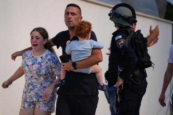 Israeli police officers evacuate a family from a site hit by a rocket fired from the Gaza Strip, in Ashkelon, southern Israel.