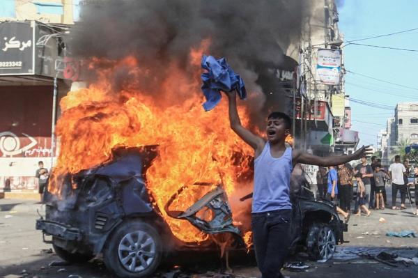 A Palestinian boy reacts next to a burning Israeli vehicle that Palestinian gunmen brought to Gaza.
