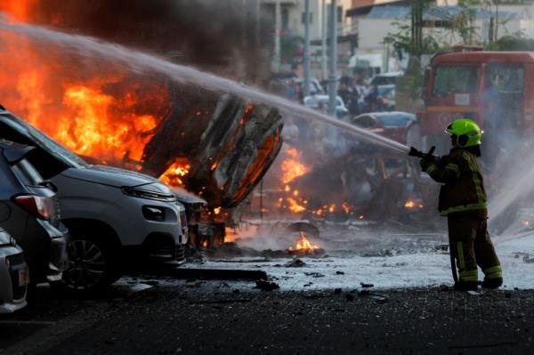 An emergency personnel works to extinguish fire after rockets were launched from the Gaza Strip, in Ashkelon, Israel October 7, 2023.